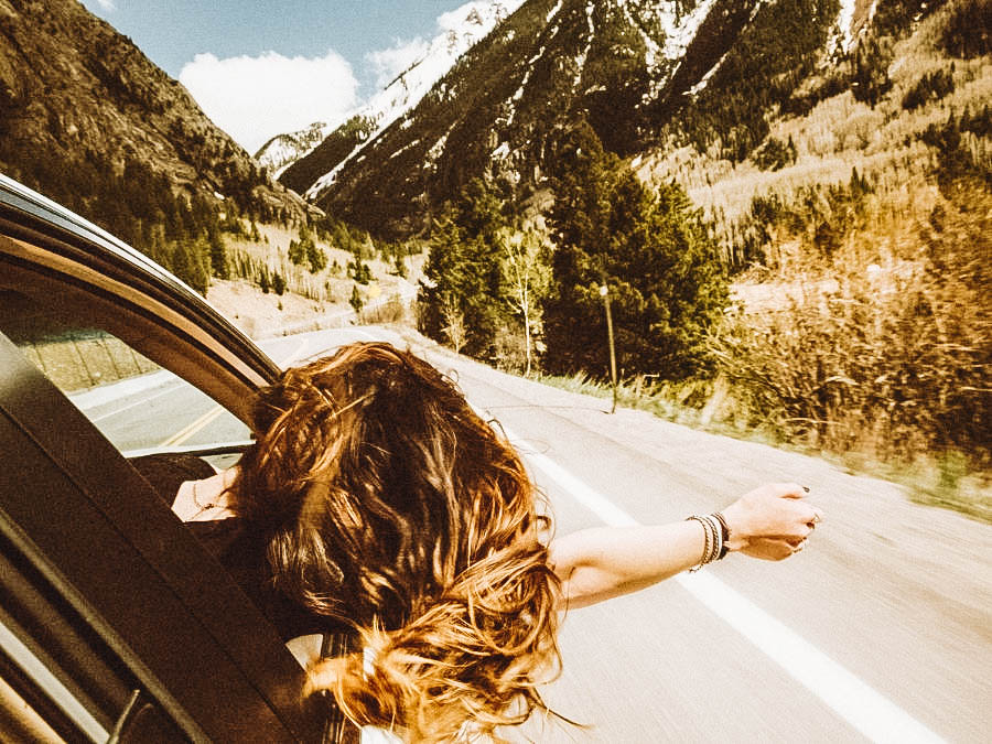 A woman enjoying the fresh air while on a road trip