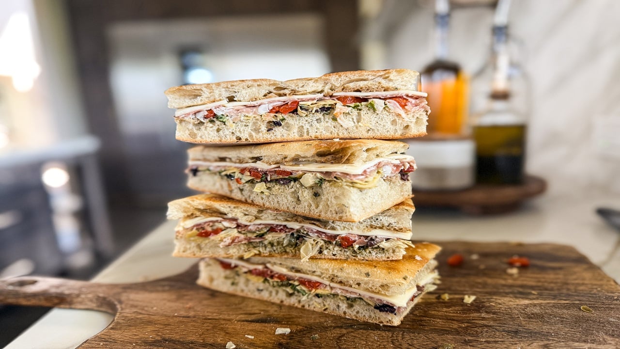 stacked sandwichs on a wooden cutting board