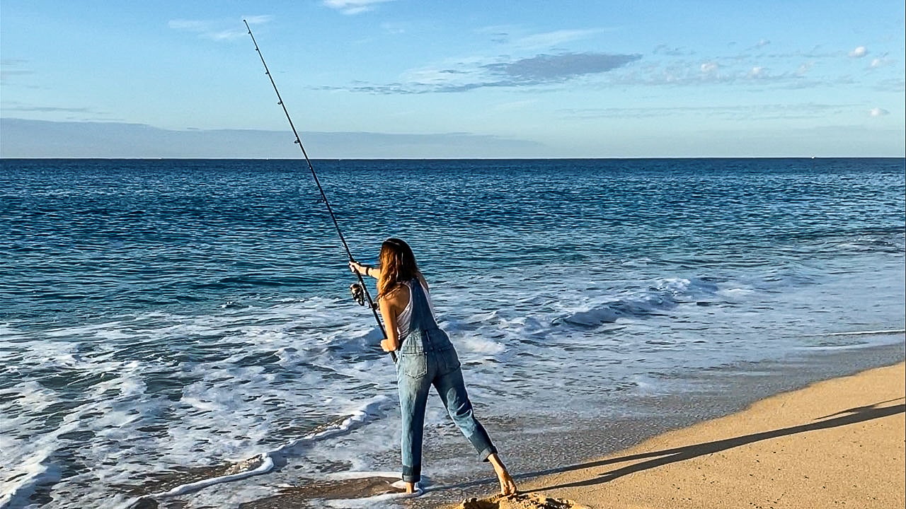 women in overalls fishing in the ocean