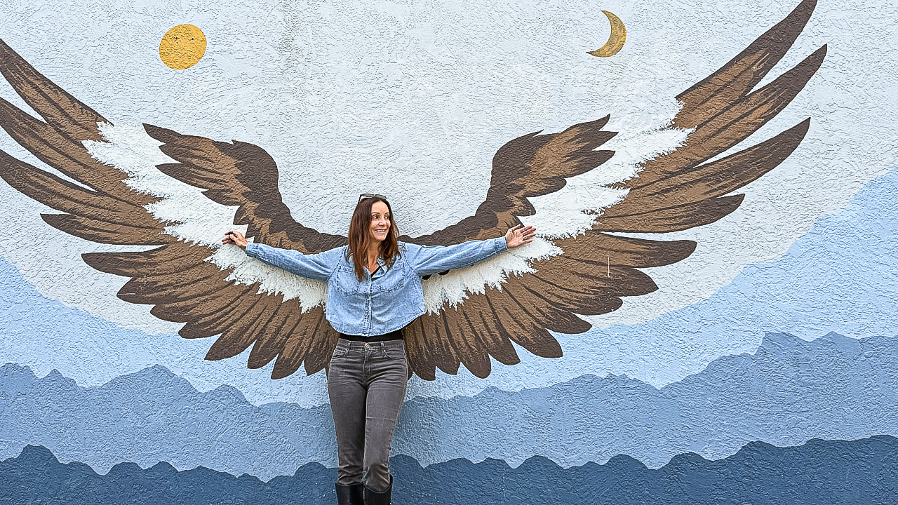 women standing in front of a wings mural.