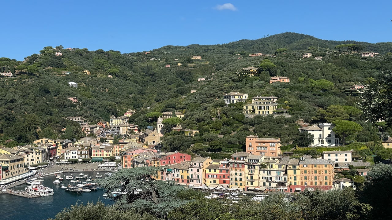 Colorful waterfront city with boats and mountains in the background