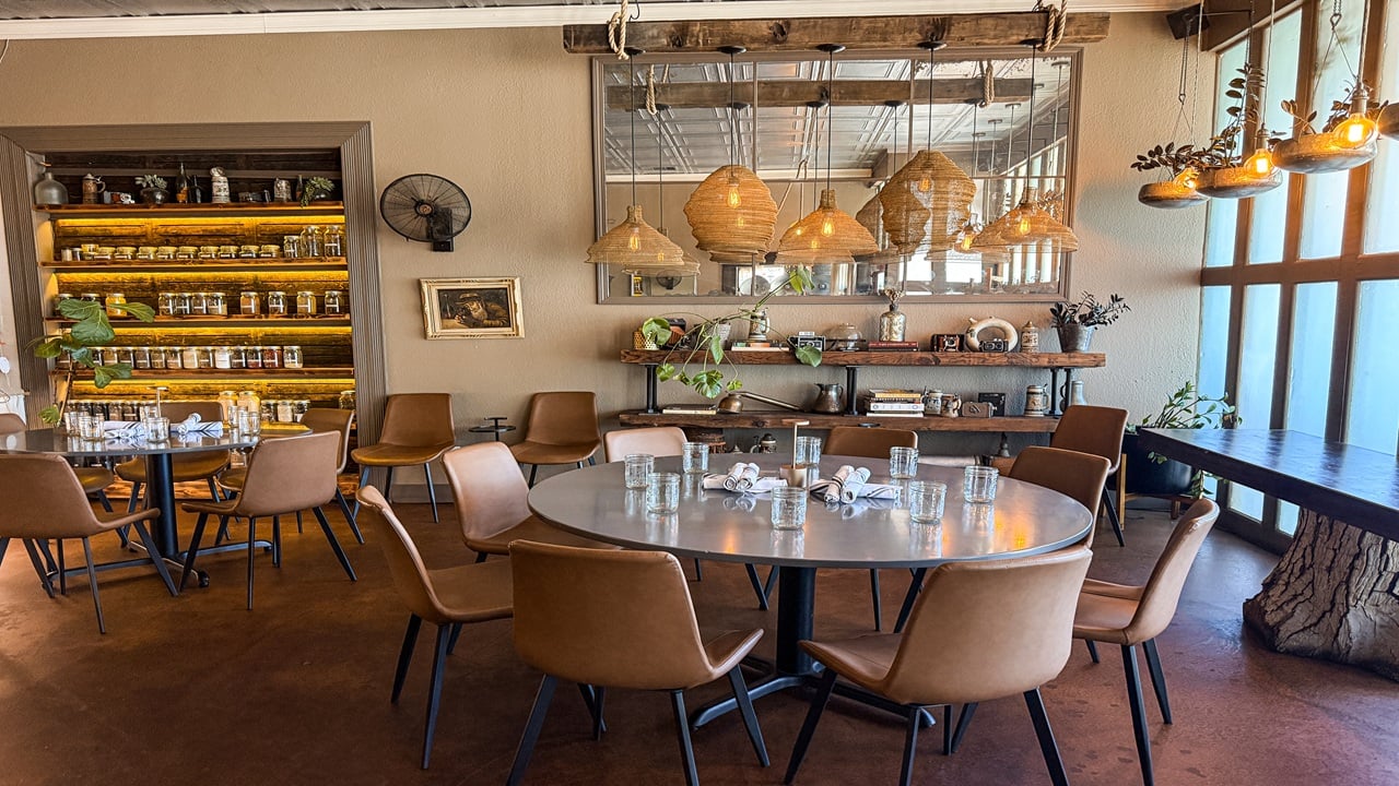 Restaurant dining room with two set tables and hanging rattan chandeliers