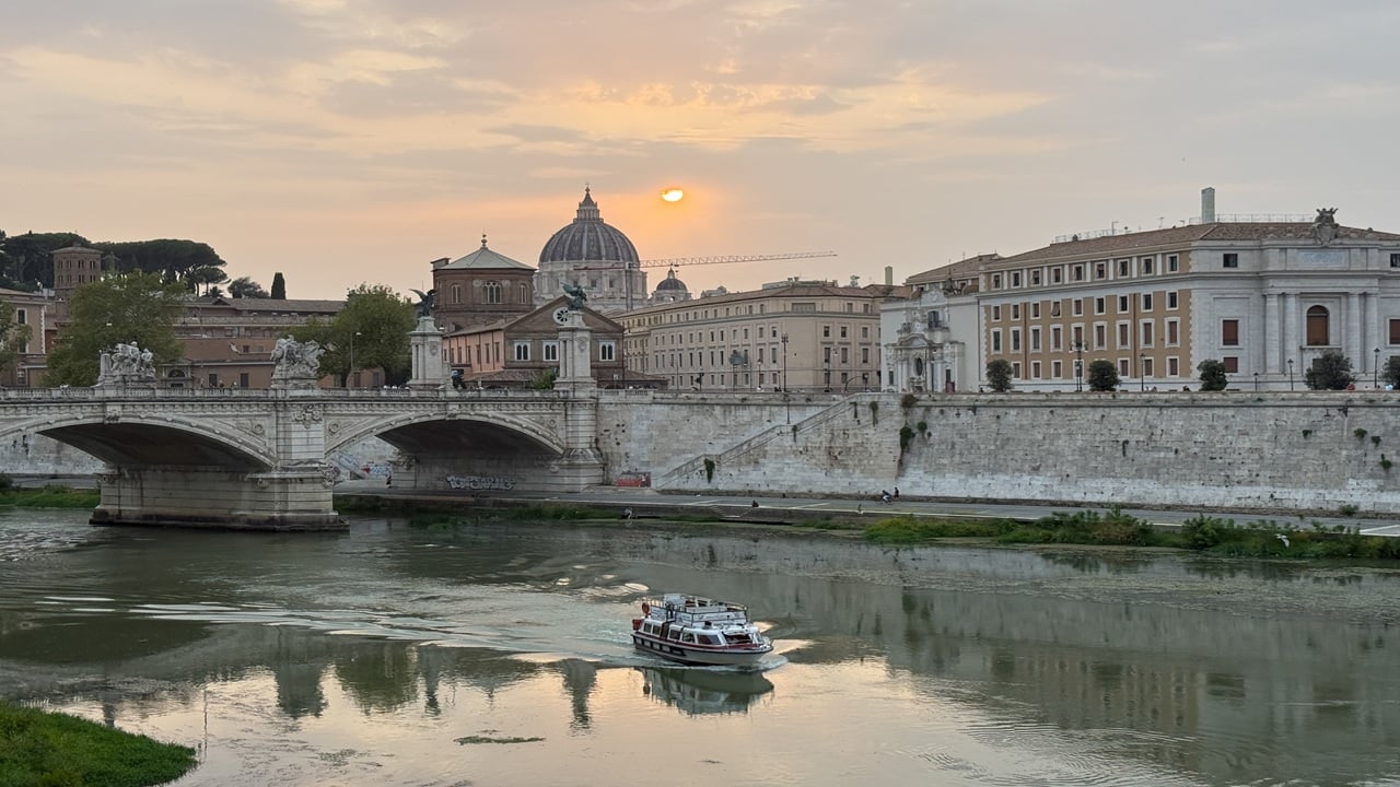 Boat on the river with arches and an ancient city in the background