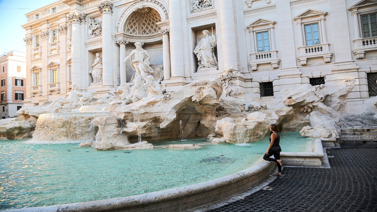 Ancient white building with sculptures, a fountain and a woman
